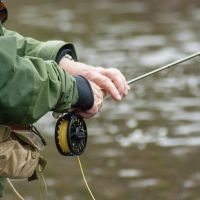 Fly-fisherman holding rod and reel