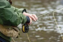 Fly-fisherman holding rod and reel