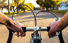 first-person view over handlebars riding a bike on a suburban street