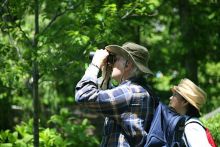 man and woman watching birds in forest